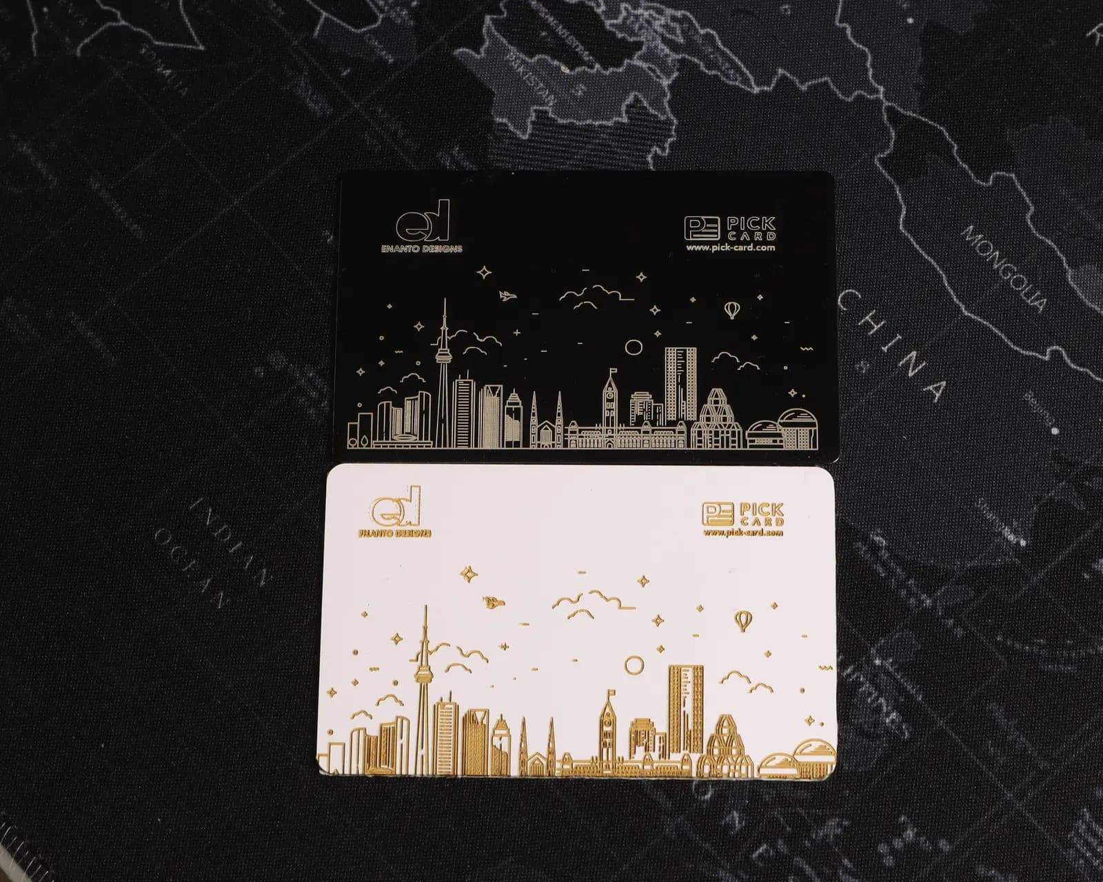 Finished Pick Card metal and PVC business cards photographed on a dark map surface